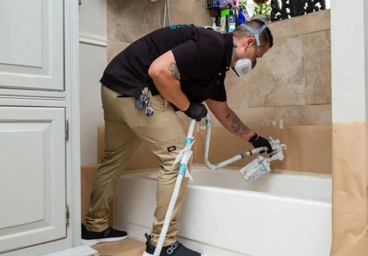 worker refinishing bath tub